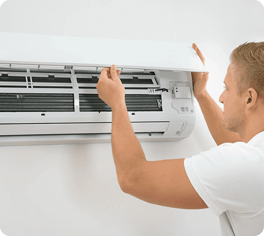 A man is fixing the air conditioner on the wall.