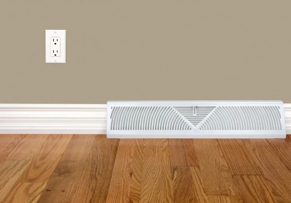 A white radiator cover sitting on top of a hard wood floor.