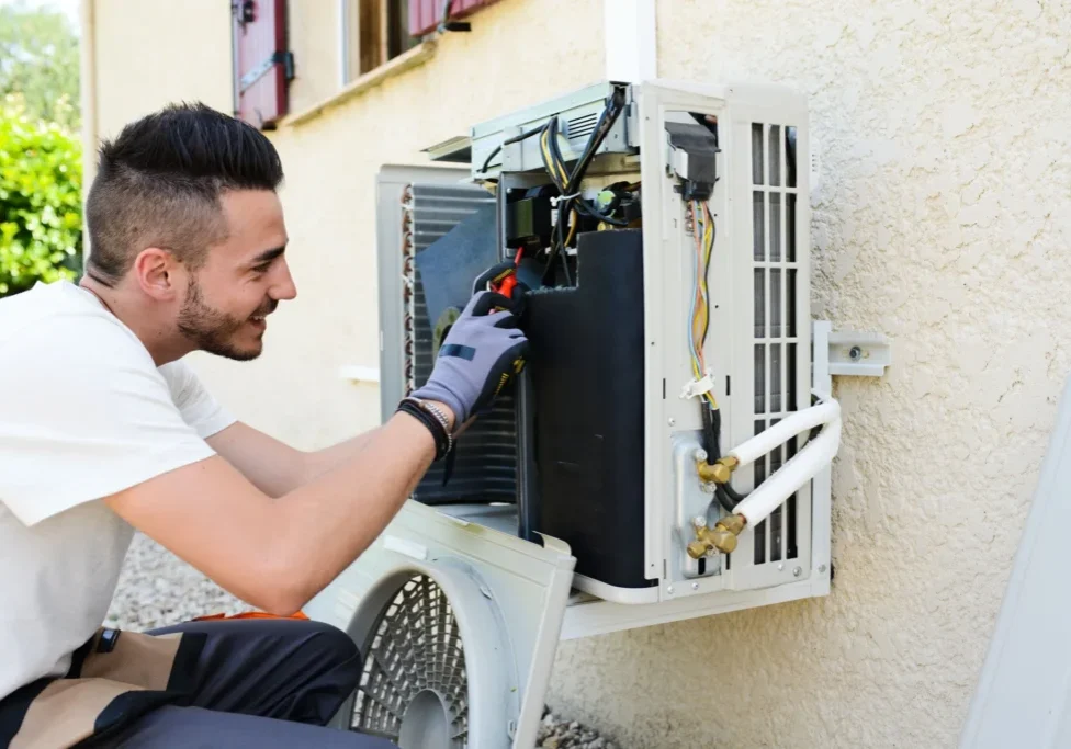 A man fixing an air conditioner outside