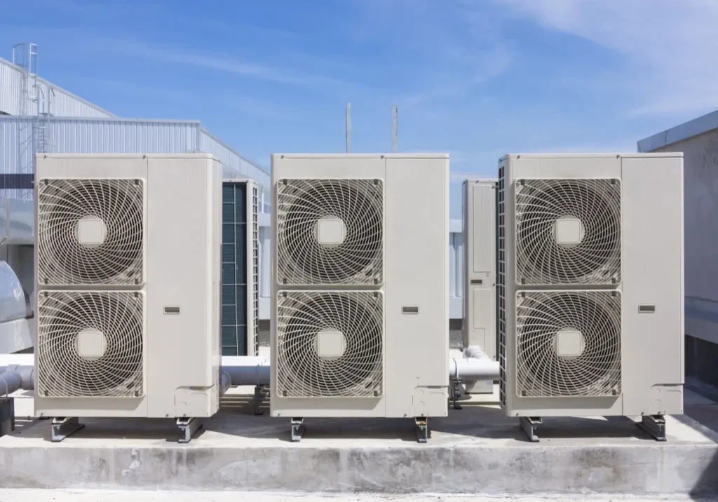 A group of air conditioners sitting on top of concrete.